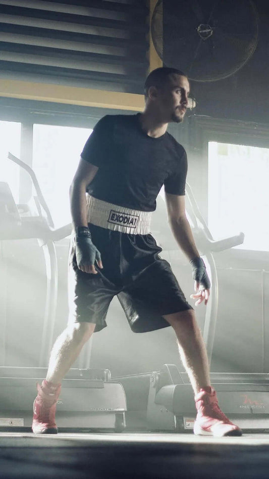 Man wearing Exodia 1 Sports satin Boxing Shorts with white waistband and black fabric in gym